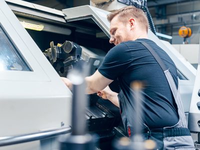 Experienced worker changing tool setup of lathe machine on the factory floor